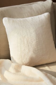 two white pillows sitting on top of a couch