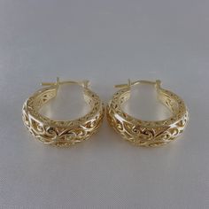 Step into the world of elegance and style with our stunning Gold Plated Filigree Hoop Earrings. Designed to make a statement, these earrings add a touch of glamour to any ensemble. Get ready to turn heads and feel fabulous!Inner diameter: 18mm - 11/16 in.Outer Diameter: 25mm - 1 in.Width at the bottom: 9mm - 3/8 in. Elegant Hoop Earrings With Intricate Design For Wedding, Elegant Intricate Hoop Earrings For Wedding, Elegant Hoop Clip-on Earrings For Anniversary, Small Hoop Filigree Earrings As Gift, Gold Hoop Earrings With Intricate Design, Small Filigree Hoop Earrings As Gift, Elegant Metal Hoop Earrings With Filigree, Small Hoop Earrings For Formal Events, Intricate Design Hoop Earrings For Wedding