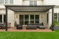 an outdoor living area with couches, tables and chairs on the grass in front of a house