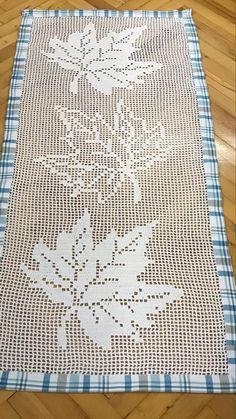 a white doily on a wooden floor with blue and white plaid material in the background