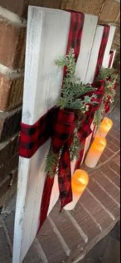 some candles are hanging on the side of a building with red and black plaid ribbon