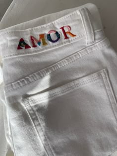 an embroidered name on the back of a pair of white pants with colorful letters in red, blue, yellow and green