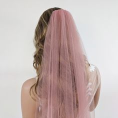 the back of a woman's head wearing a pink veil