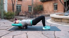 a woman is doing an exercise on a yoga mat in front of a pink building