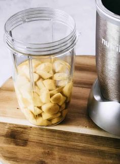 a blender filled with macaroni and cheese on top of a wooden cutting board