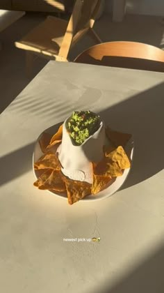 a white plate topped with chips and guacamole on top of a table