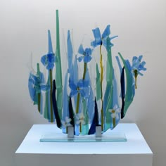 a glass sculpture with blue flowers and green stems