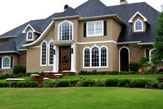 a large house with lots of windows on the front and side of it, surrounded by lush green grass