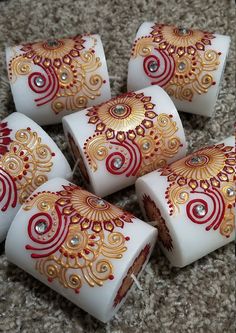 six white and gold decorated candles sitting on top of a carpeted floor next to each other