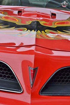 the front end of a red sports car with flames on it's grills