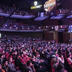 a large crowd of people sitting in front of a stage at a convention or conference