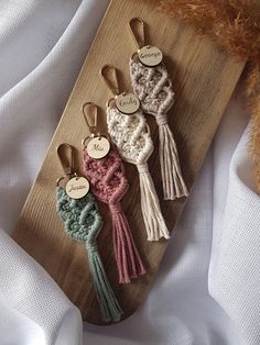 four crocheted key fobs with name tags on them sitting on a wooden board