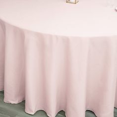 a round table with pink linens and white napkins on the top is set up for an event