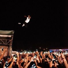 a man flying through the air while riding on top of a skateboard in front of a crowd