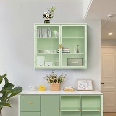 a kitchen with green cabinets and plants in the corner on the counter top, next to a potted plant