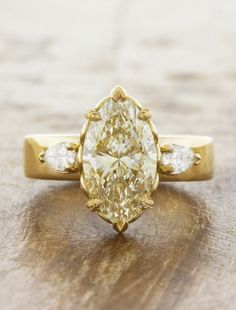 a fancy yellow diamond ring with three diamonds on the band and an oval shaped center stone