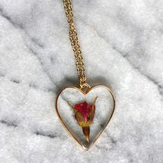 A single rose for the perfect gift for the unique gal in your life. A rose is encased in jewelry grade resin, within an antique bronze or gold plated heart bezel. The bezel is 1 1/2 inches in length and 1 1/4 inches in width- the matching chain is 24 inches. Chain is finished with a lobster clasp. Necklace will arrive attached to card shown in photos. Ready to be gifted! This necklace is custom made. Just like nature, no two will be exactly alike! Let me assure you, though, that we replicate eac Rose Heart-shaped Jewelry Gift, Rose-colored Heart-shaped Jewelry For Gifts, Rose Heart-shaped Jewelry For Gift, Heart-shaped Rose Colored Jewelry For Gift, Heart-shaped Rose Jewelry For Gift, Rose Heart-shaped Necklace For Gift, Valentine's Day Gift Jewelry With Rose Design, Rose Jewelry For Valentine's Day, Rose Valentine's Day Necklace With Flower Charm