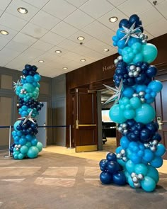 two tall blue and silver balloons are in the middle of an empty room with lights on