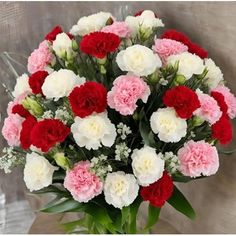 a bouquet of red, white and pink carnations in a vase on a table