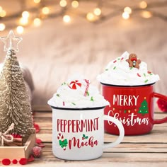 three coffee mugs with christmas decorations on the table next to a small christmas tree