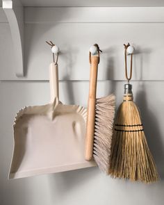 two brooms and a dustpan hanging on the wall