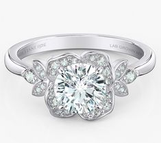 a white gold engagement ring with an intricate flower design on the center and side stones