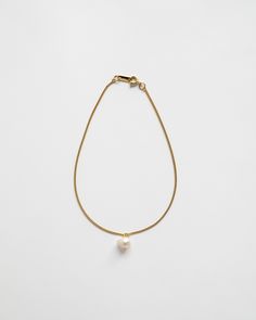 This anklet consists of a minimalistic chain, elegantly accented with a single luminous freshwater pearl drop. Gold Pearl Anklet With Pearl Charm, Gold Dainty Anklets With Pearl Charm, Elegant Everyday Chain Bracelet With Pearl Drop, Elegant Pearl Drop Chain Bracelet For Everyday, Dainty Gold Anklets With Pearl Charm, Dainty Pearl Gold Anklets, Gold Anklets With Pearl Charm For Gift, Gold Anklets With Pearl Charm As Gift, Gold Pearl Anklets As Gift