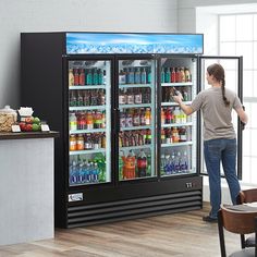 a woman standing in front of a refrigerator filled with drinks