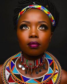 an african woman with colorful jewelry on her neck and necklace, looking at the camera