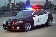 a police car with its lights on is parked in the parking lot next to some buildings