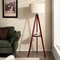 a living room with a green couch and a wooden tripod lamp in the corner