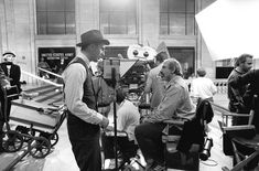 black and white photograph of two men talking to each other in front of microphones