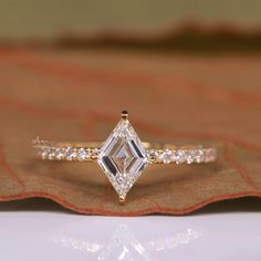 a diamond ring sitting on top of a cloth covered tablecloth with an orange and white background