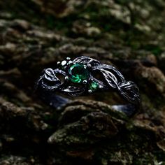 This oxidized silver engagement ring has a design that was inspired by nature and is made up of entwined branches and leaves. A splash of vivid green is added to the design by three exquisite emeralds that are tucked between the leaves. This ring is the perfect option for a fan of nature or someone who values good craftsmanship because the complex branches and green gemstones symbolize the beauty and tenacity of the natural world.  Characteristics: Metal - Recycled solid sterling silver  Stone - Cubic Zirconia Finish - Oxidized. View all silver branch rings: https://www.etsy.com/shop/TinyShinyJewel?ref=seller-platform-mcnav&section_id=43346778 Care instructions: To care for the ring, avoid contact with water and chemicals such as perfumes and lotions. When the ring is not in use, store it Fantasy Sterling Silver Ring, Mystical Green Gemstone Jewelry, Silver Fantasy Promise Ring, Sterling Silver Fantasy Style Promise Ring, Sterling Silver Fantasy Ring, Silver Fantasy Rings For Anniversary, Fantasy Silver Rings For Anniversary, Fantasy Style Silver Ring For Anniversary, Magical Promise Ring Jewelry