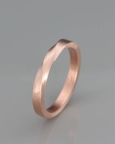 a wedding ring made out of pink gold, on a grey background with the word love written in it