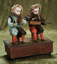 two dolls sitting on top of a wooden box with an arrow in its mouth and another doll standing behind them