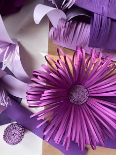 purple and white paper flowers sitting on top of each other