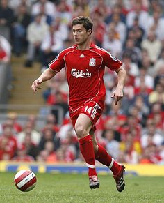 a soccer player running with the ball in front of an onlooking crowd