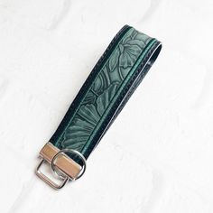 a green leather belt with a metal buckle