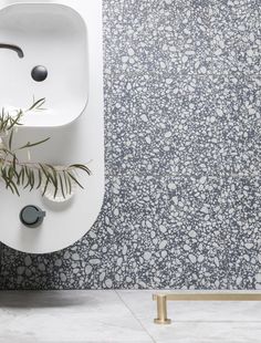 a white sink sitting on top of a wall next to a plant in a vase