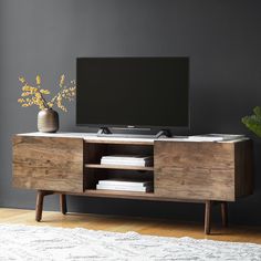 an entertainment center with a flat screen tv on it's stand, in front of a gray wall