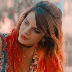 a woman with red and orange hair is looking at the camera while wearing a necklace