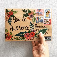 someone is holding up a postcard with the words you're awesome written on it