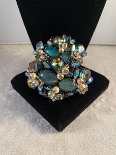 "This is an extremely rare and beautiful SPARKLING Hobé brooch and bracelet demi parure fully encrusted in large and small saphiret glass cabochons/stones that exhibit turquoise-pink-brown tones. All pieces are accented with rhinestone topped pearls and small green and orange round rhinestones and several blue-green metallic finished navettes! The other quite unique addition are the small arrow-shaped clusters of tiny AB rhinestones surrounding the pearls that move freely. It really is such a beautiful set, and must be seen in person to appreciate - I tried to capture the beauty of the saphiret stones which is difficult to do in a picture. The glass was made in the first half of the century by adding gold to sapphire blue glass (the earlier the piece the pinker tone of the stone), creating Unique Multicolor Evening Jewelry, Costume Jewelry Brooch For Evening, Unique Evening Bracelet Jewelry, Evening Costume Jewelry Brooch, Multicolor Brooch For Evening Wear, Unique Jeweled Bracelets For Formal Occasions, Multicolor Brooch Jewelry For Evening, Multicolor Party Jewelry With Brooch, Unique Multicolor Jewelry With Brooch