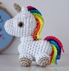 a small crocheted unicorn toy sitting on top of a white table next to a wall