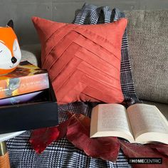 an open book on a couch next to a pillow and a stuffed animal with its eyes closed