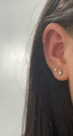 a close up of a person's ear with two small diamond studs on it