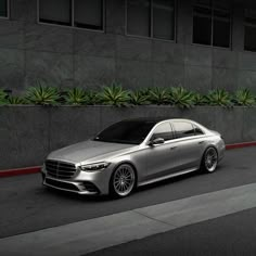 a silver car parked on the side of a road next to a tall gray building