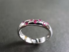 A wedding band with ruby made in 14k white gold. Product Specifications: Type: Natural Ruby Number of Gemstones: 7 Precious Metal: 14K Gold Ring Width: 3.90mm Currently made to order pieces may take up to 10 business days to complete, or let me know if you need it urgent. You may also like: A similar ring with diamond, https://www.etsy.com/listing/65904988/diamond-wedding-ring-in-14k-white-gold It's easy to create jewelry that's perfect for you. Change the materials to suit your style and budget Pink Sapphire Gemstone Wedding Ring, Luxury Ruby Birthstone Ring For Wedding, Wedding Rings With Brilliant Cut Pink Sapphire, Elegant Pink Sapphire Wedding Birthstone Ring, Wedding Rings In Diamond White Pink Sapphire, Wedding Rings With Pink Sapphire And Accent Stones, Fine Jewelry Pink Sapphire Birthstone Ring For Wedding, Pink Sapphire Multi-stone Wedding Ring, Wedding Ruby Ring With Brilliant Cut In Diamond White