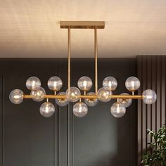 a modern chandelier with clear glass balls hanging from it's brass frame